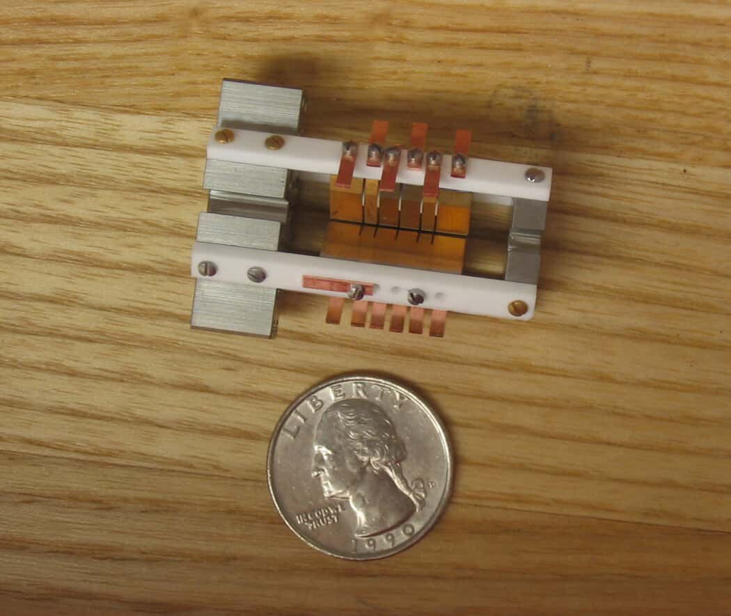 The ion trap at the heart of a NIST aluminum-ion atomic clock, a device that isolates single charged atoms in quantum states, shown beside a coin for scale
